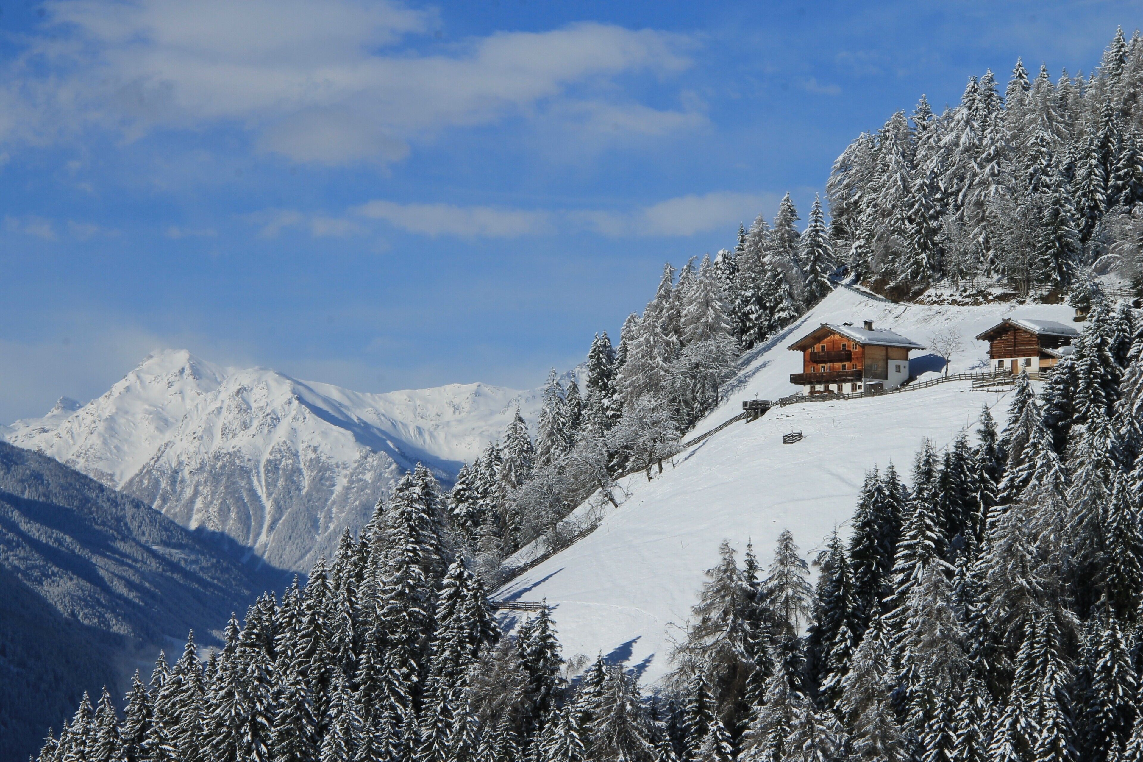 Une montagne enneigée, avec un chalet en bois situé sur un versant.