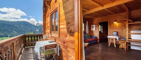 Eine Holzhütte mit Balkon, einem Essbereich und einem Wohnzimmer mit Sofa und Tisch.