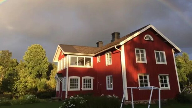 Ein rotes Haus mit weißem Fensterrahmen und einem Schornstein.