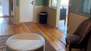Ein Zimmer mit Holzboden, einer weißen Tür, einem braunen Ledersessel und einer Deckenleuchte.