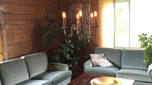 Ein gemütlicher Raum mit zwei grauen Sofas, einem Holztisch mit einer Landkarte und einer Chandelier.