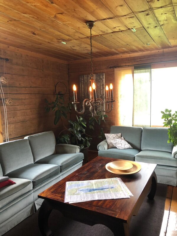 Una habitación acogedora con dos sofás grises, una mesa de centro de madera con un mapa, y una araña.