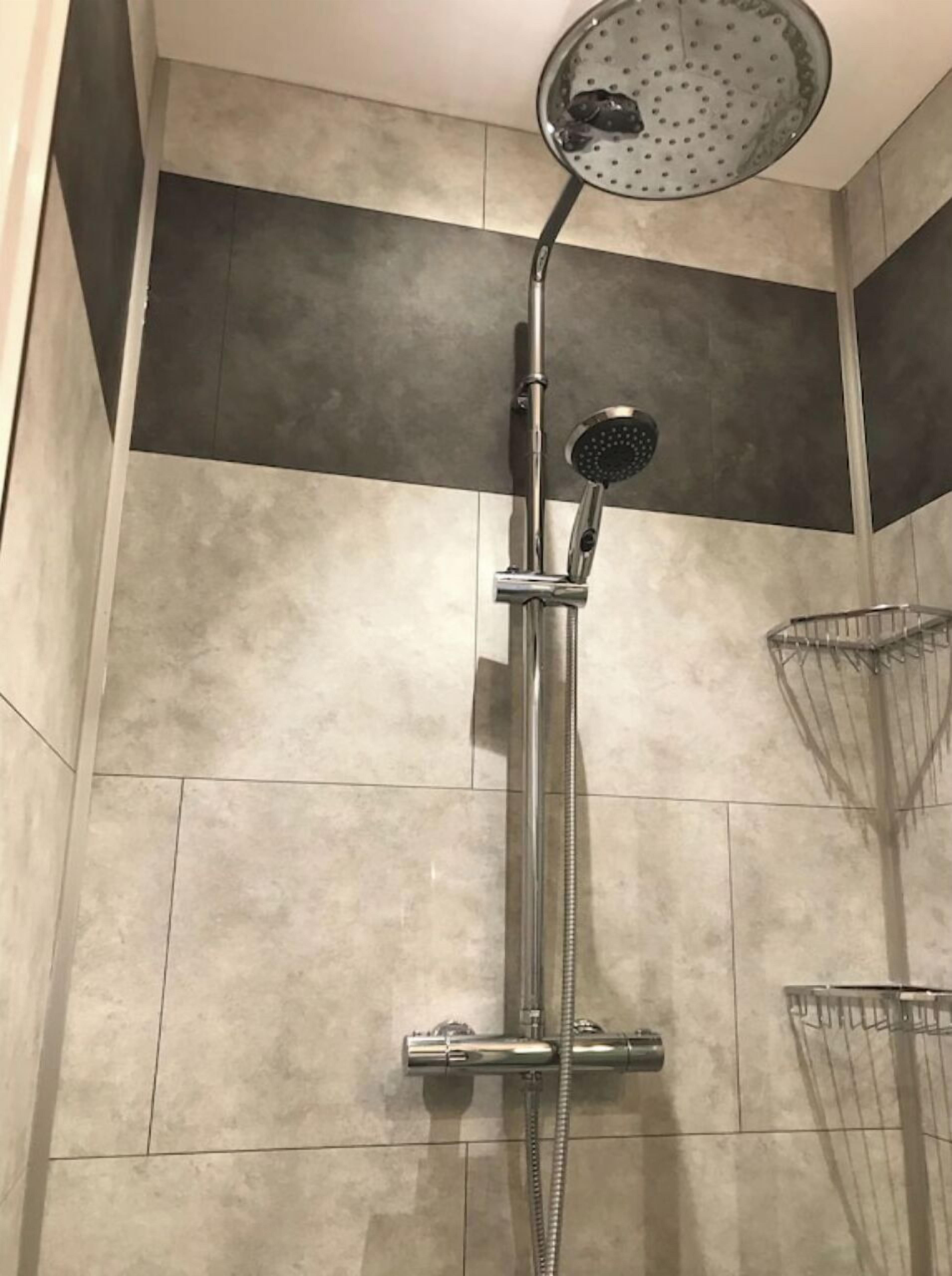 A shower with a handheld showerhead and a wall-mounted rain showerhead.