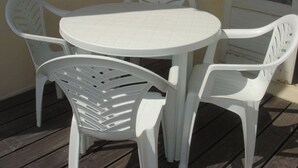 A round white table with four white chairs, set on a wooden deck. - Pacific Apartment (Fort-Mahon-Plage)