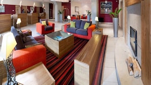 Un hall d’entrée spacieux au design moderne, comprenant différents espaces de détente et une table basse centrale.