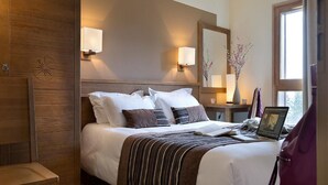 Une chambre d’hôtel avec un grand lit, des lampes de chevet, une table de nuit, un ordinateur portable et une fenêtre donnant sur un beau paysage.