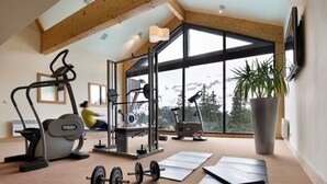 Une salle de sport équipée de matériel d’exercice, dotée de grandes fenêtres et offrant une vue sur les montagnes.