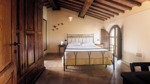 Een slaapkamer met een houten plafond, een bed met een metalen frame, een houten garderobe en een klein nachtkastje.