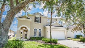 A two-story house with a garage, a front porch, and a well-maintained lawn. - ⭐⭐Modern 5 Bed, 4 Bath Home on Calabay Parc | Private Pool | Minutes to Disney⭐⭐ (Davenport)
