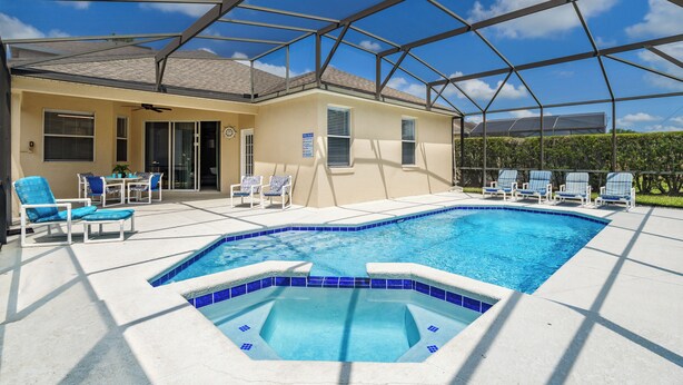 A covered outdoor swimming pool with blue-tiled edges, surrounded by lounge chairs and a patio area. - ⭐⭐Modern 5 Bed, 4 Bath Home on Calabay Parc | Private Pool | Minutes to Disney⭐⭐ (Davenport)