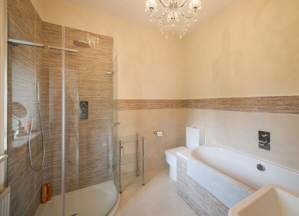 Une salle de bain moderne dotée d’une douche à parois de verre, d’une baignoire sur pieds et d’un meuble-lavabo avec un miroir.