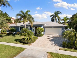A residential house with a driveway, palm trees, and a garage.