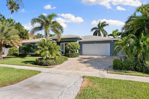 A residential house with a driveway, palm trees, and a garage.