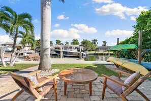 An outdoor seating area with a round wooden table and two wicker lounge chairs.