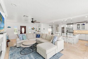 A modern living room with a sectional sofa, a round coffee table, and a ceiling fan.