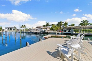 A marina with boats, a wooden deck, and lounge chairs.