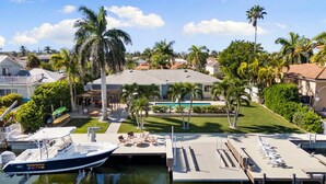 Un puerto deportivo con un barco amarrado, una piscina y un edificio con terraza en la azotea.