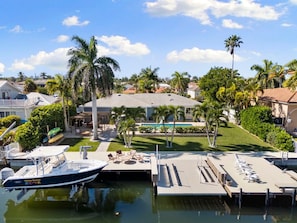 A marina with a docked boat, a pool, and a building with a roof terrace.