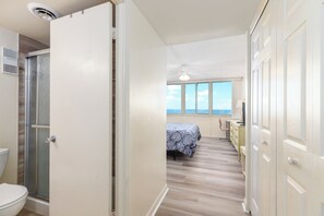 A room with a bed, a desk, and a view of the sky through large windows.