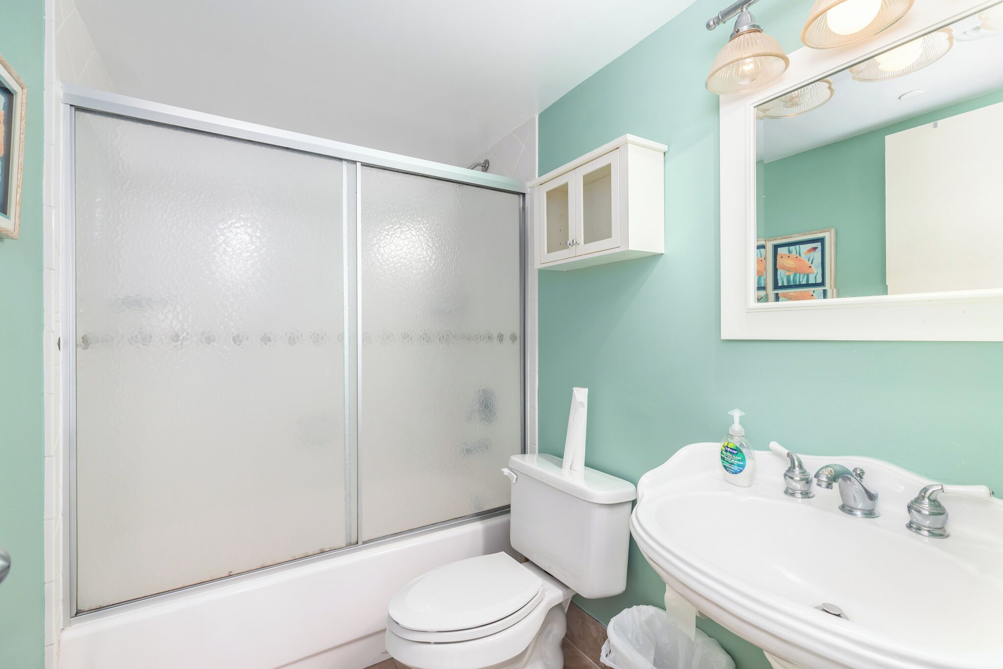 Une salle de bain comprenant des toilettes, un lavabo, un miroir et un espace douche.