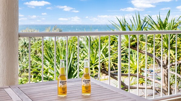 A balcony with two bottles of Corona beer, overlooking a tropical landscape with a clear sky. - Seamist 6 - Apartment w/ocean views, 80m to beach (Sunrise Beach)