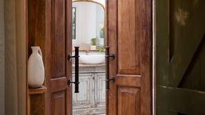 A wooden door with a handle and a mirror reflecting a bathroom with a sink and a vase. - Stockton House- light-filled retreat with art and unique flair (Daylesford)
