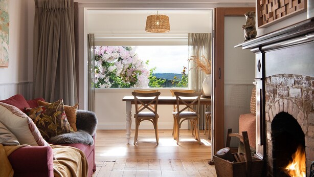 A cozy living room with a fireplace, a dining area with a view of the garden, and a comfortable seating area. - Stockton House- light-filled retreat with art and unique flair (Daylesford)