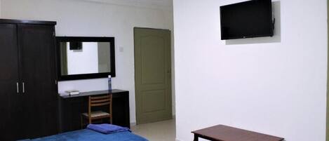 Un dormitorio con cama, escritorio, silla, televisión y armario.