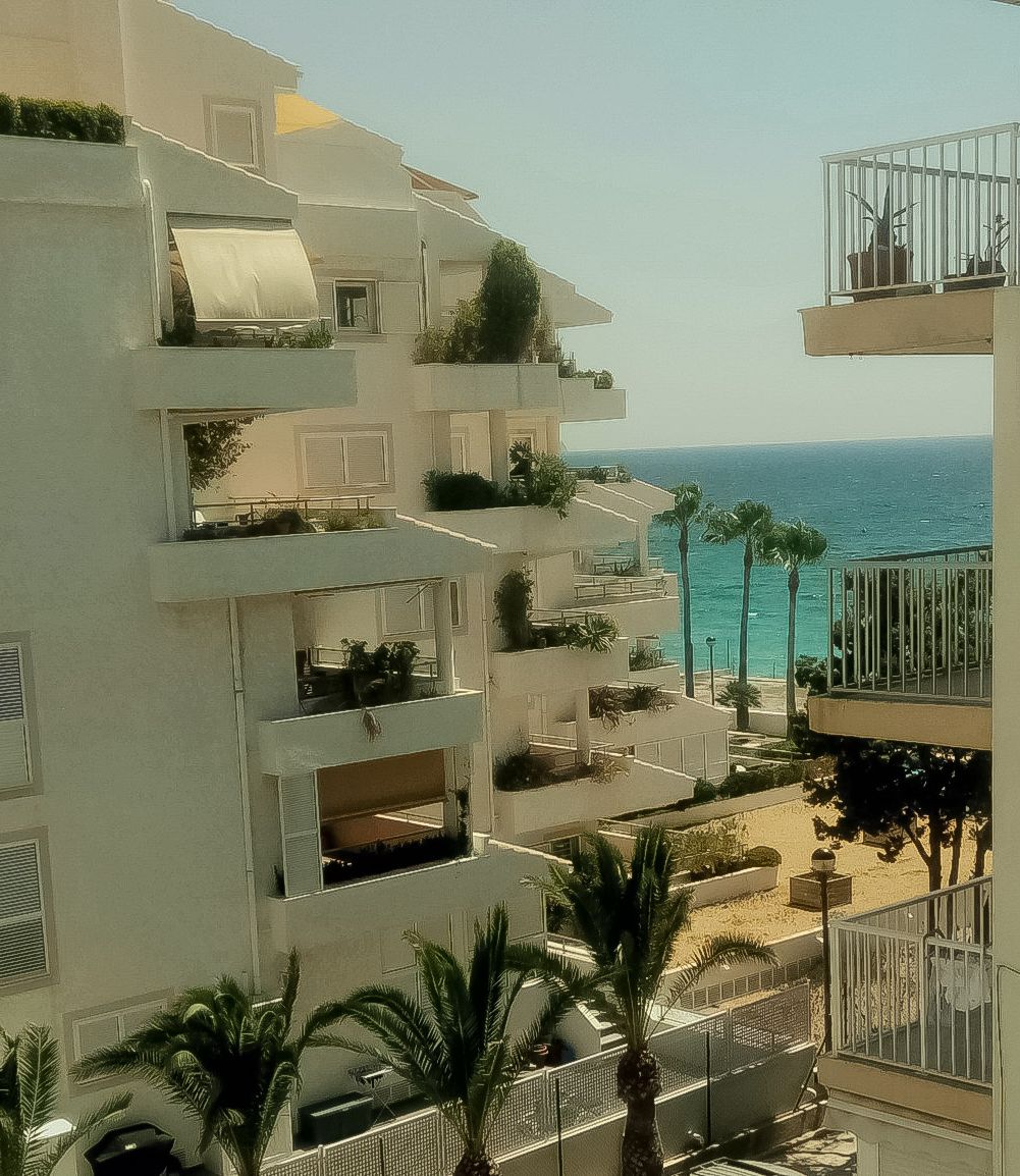 A multi-story building with balconies overlooking a beach.