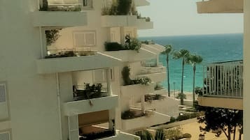 A multi-story building with balconies overlooking a beach.