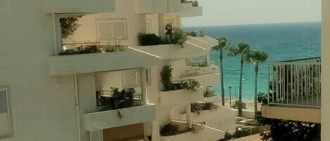 A multi-story building with balconies overlooking a beach.