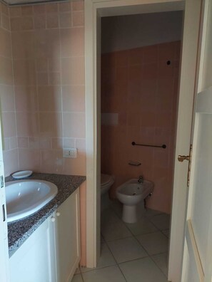 A bathroom with a sink, toilet, and bidet. - apartment with little garden five minutes walk from the beach (Trinità DAgultu e Vignola)