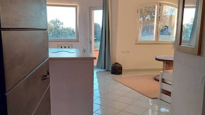 A spacious room with a large window, a ceiling fan, and a tiled floor. - apartment with little garden five minutes walk from the beach (Trinità DAgultu e Vignola)