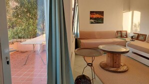 A room with a sofa, a round wooden table, and a painting on the wall. - apartment with little garden five minutes walk from the beach (Trinità DAgultu e Vignola)