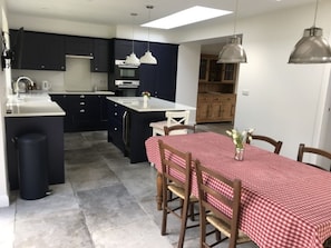 A modern kitchen with dark cabinets, a central island, and pendant lighting. - Central Modern open plan house 3 ensuite bedrooms, dog friendly. (Helmsley)