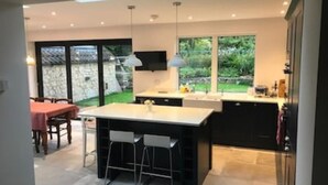 A modern kitchen with a large island, bar stools, and a dining area with a table and chairs.