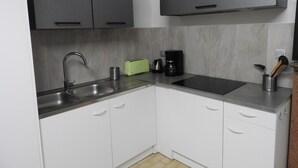 Una cocina moderna con armarios blancos, un lavamanos de acero inoxidable, un tostador verde y una cafetera.