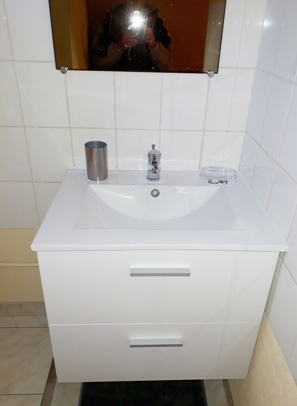 A white bathroom vanity with a sink, a mirror, and two drawers.