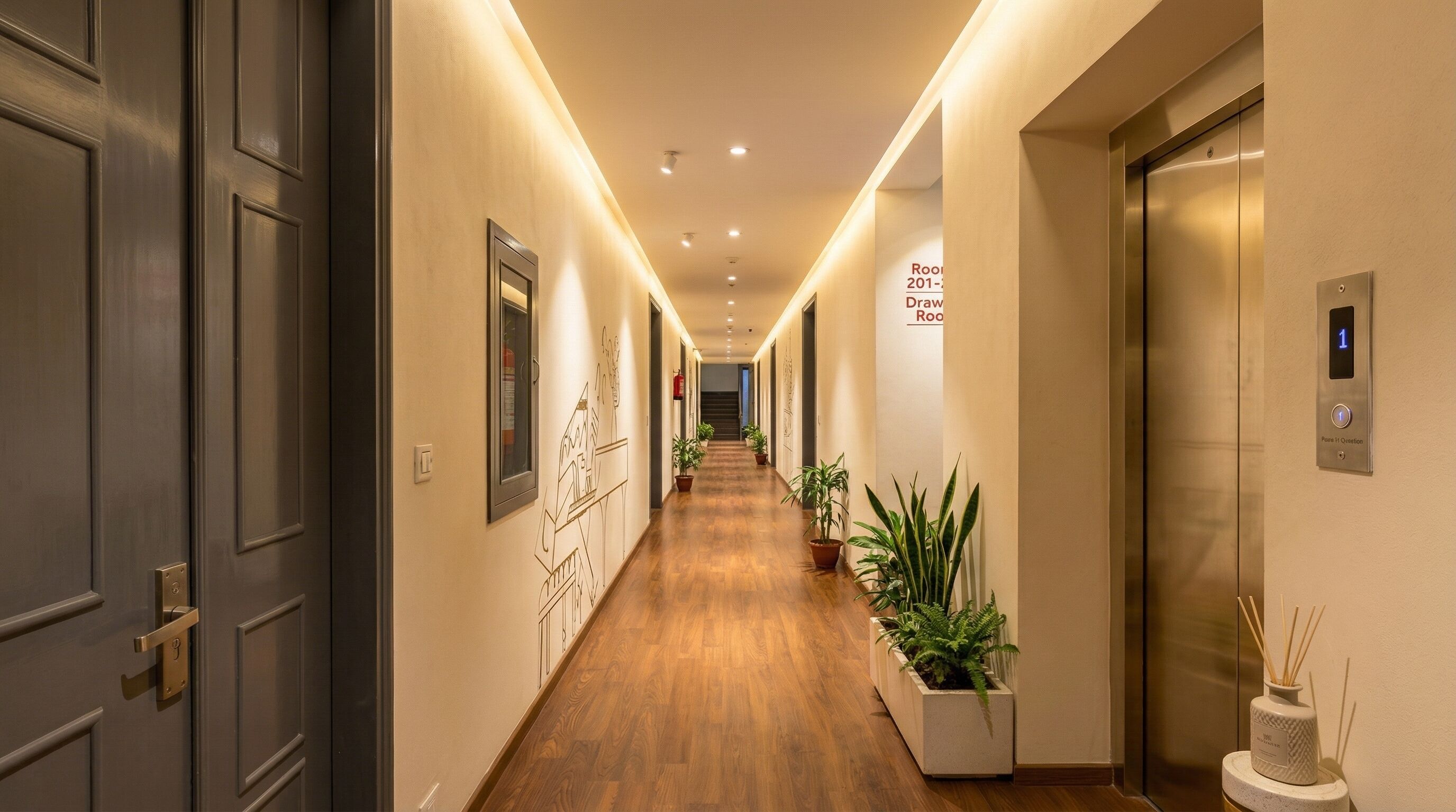 Un couloir d’hôtel avec un plancher en bois, des œuvres d’art accrochées aux murs, des plantes en pot et un ascenseur.