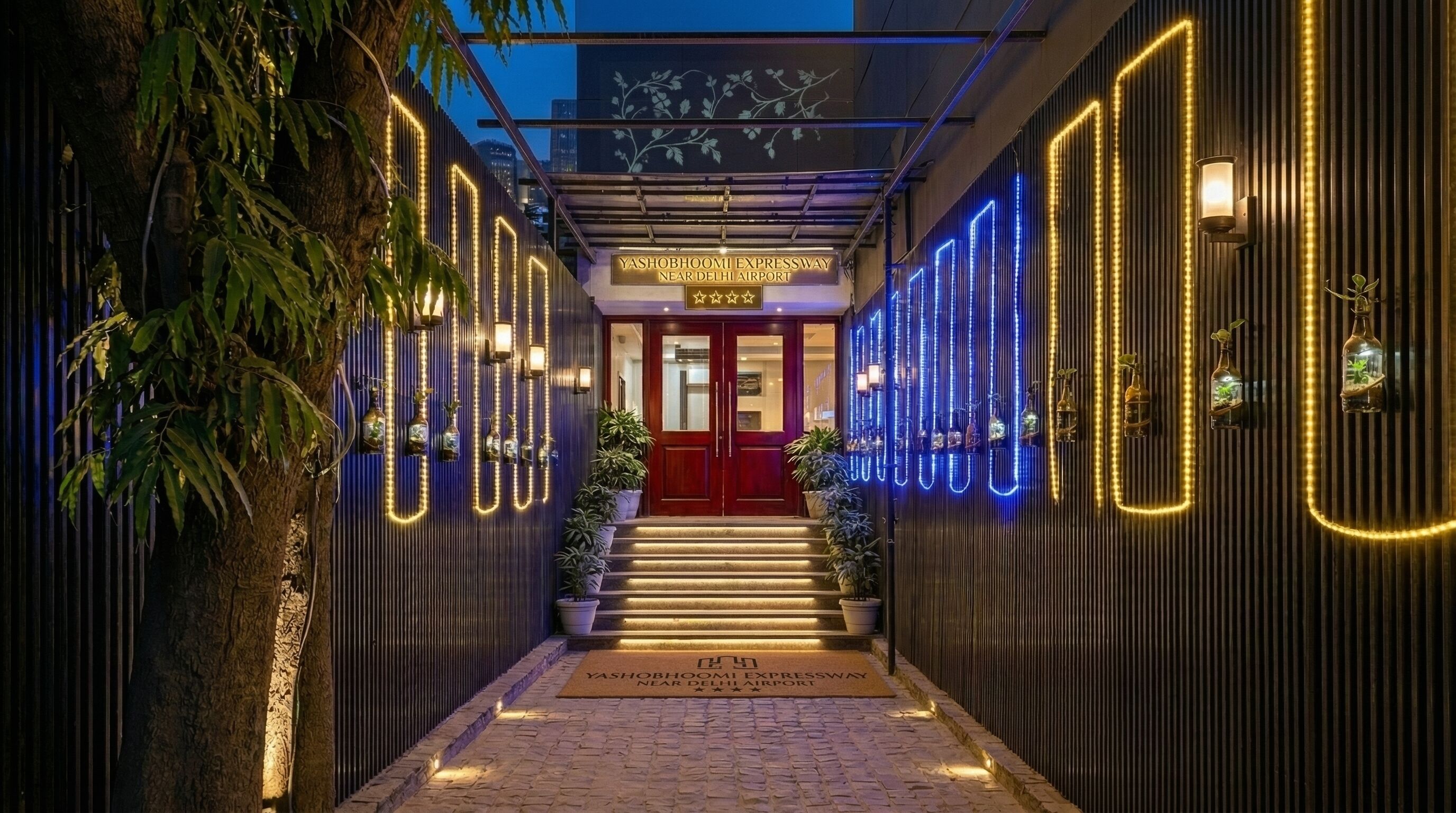 A hotel entrance with a red door, a sign above the door, and a pathway leading to the entrance.