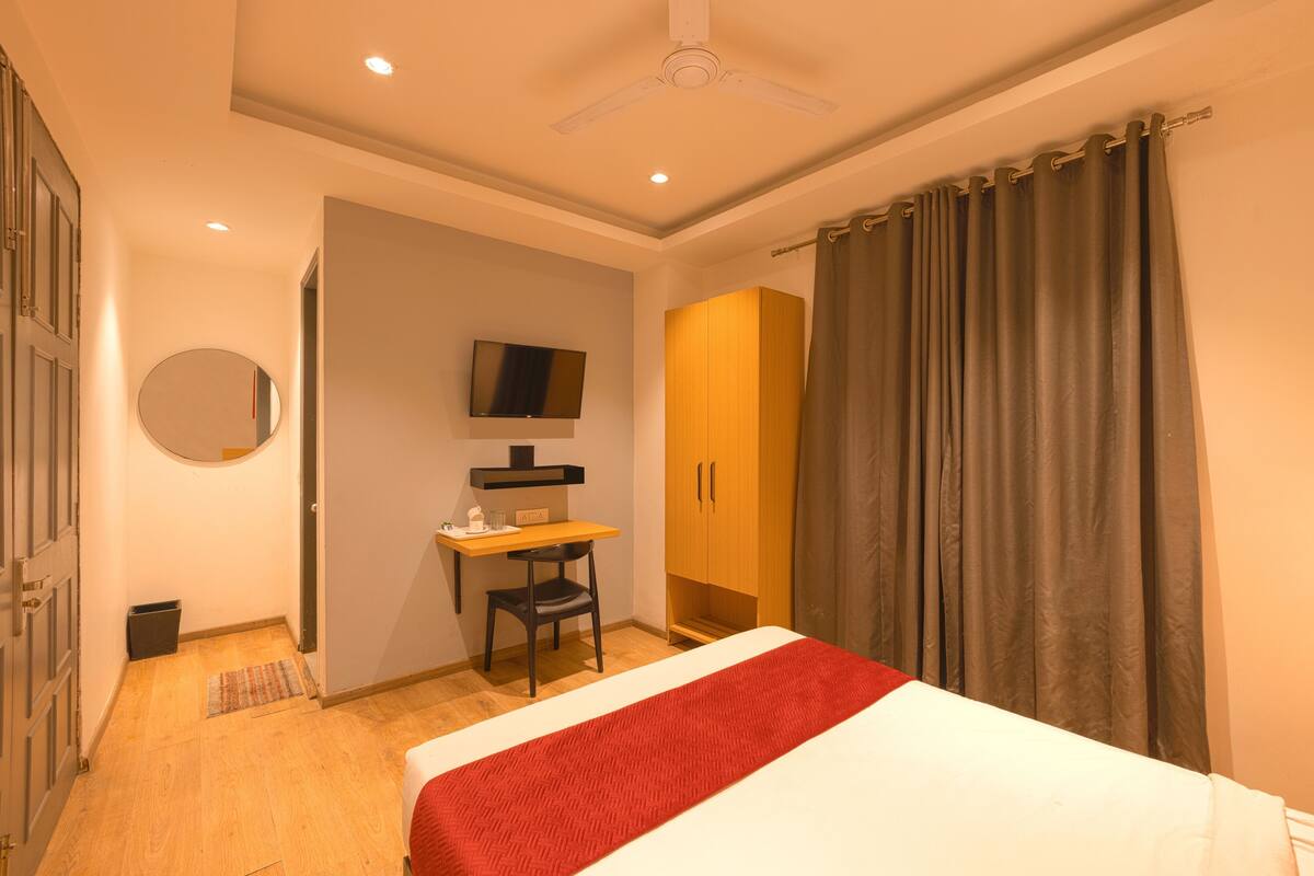 A bedroom with a bed, a desk, a chair, a television, and a wardrobe.
