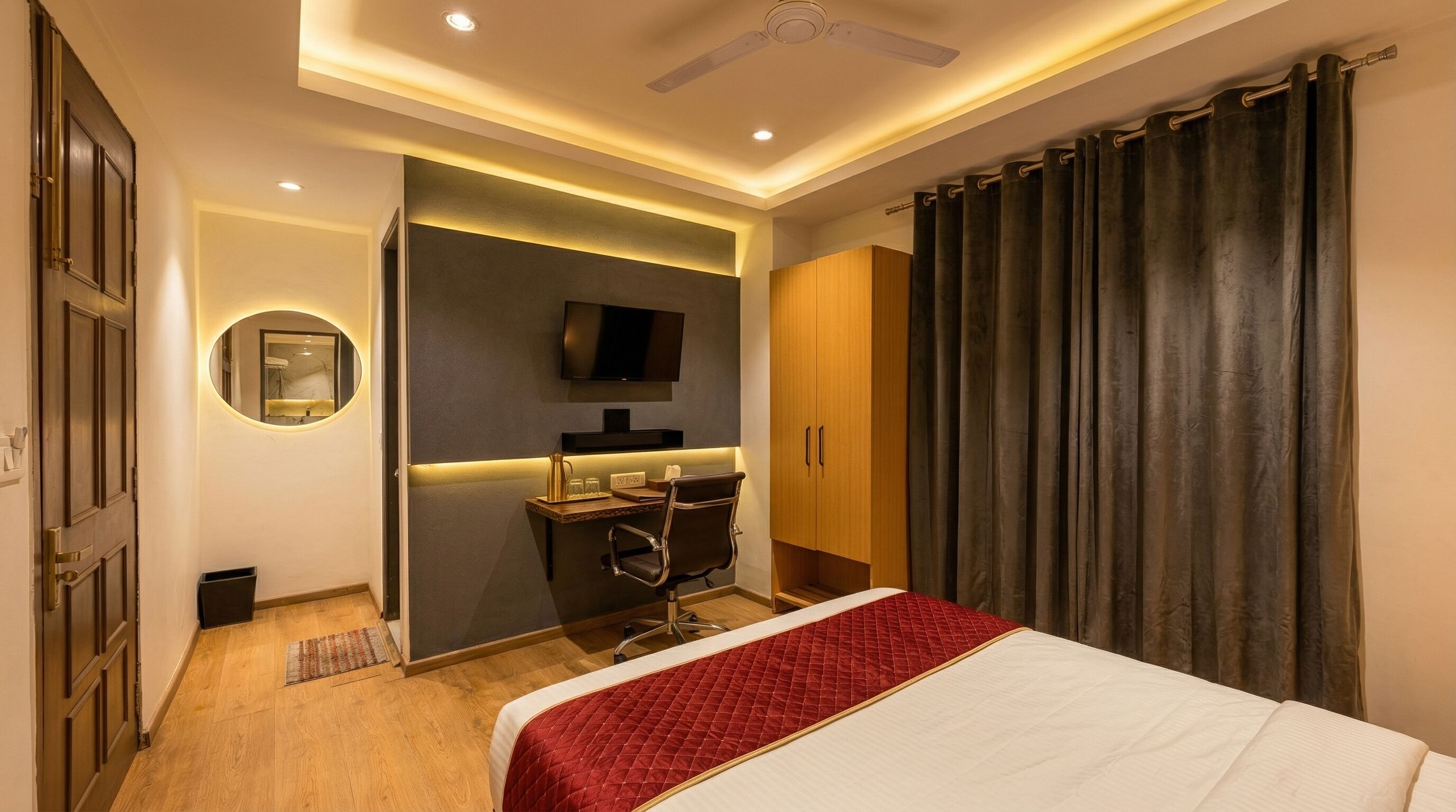 Una habitación de hotel con cama, escritorio, silla, televisor y armario.