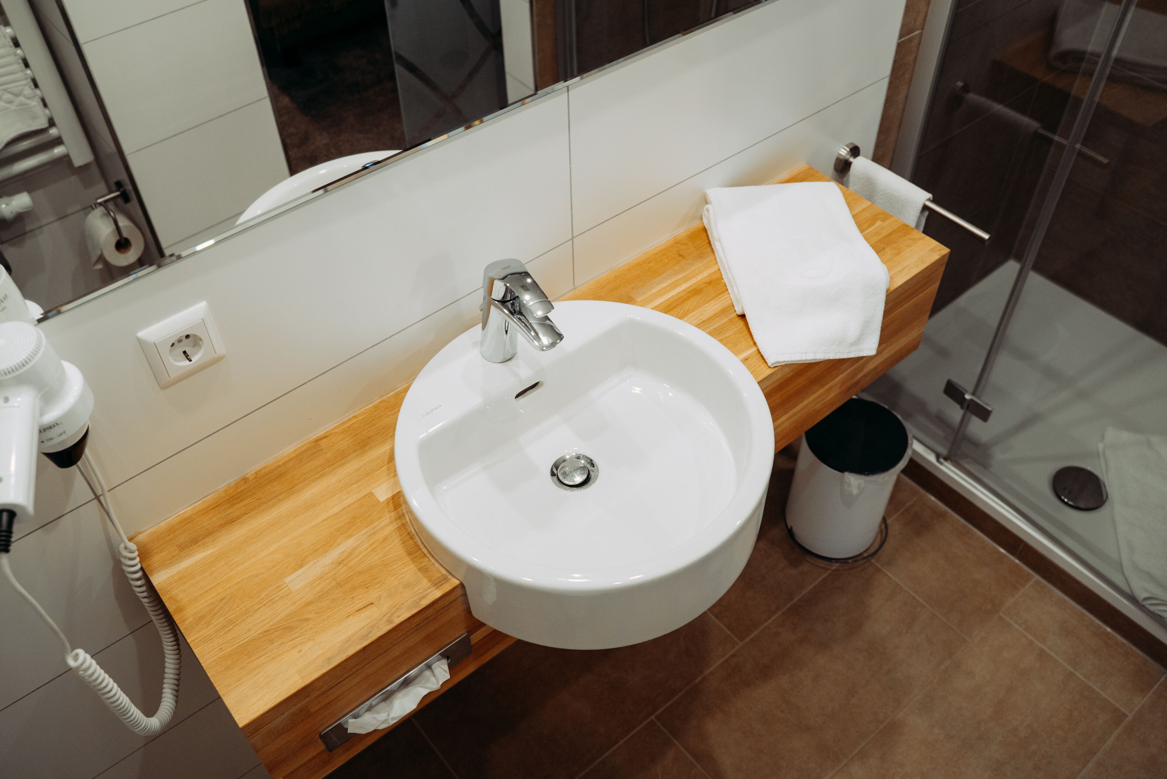 A bathroom with a white sink, wooden countertop, and a glass shower enclosure.