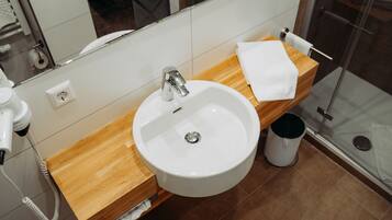 A bathroom with a white sink, wooden countertop, and a glass shower enclosure.