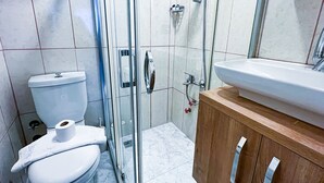 A modern bathroom with a glass shower enclosure, a toilet, and a wooden vanity with a sink. - Helen Inn  (Izmir)