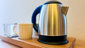 A stainless steel kettle on a wooden tray with a glass and a mug. - Helen Inn  (Izmir)