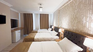 A hotel room with two beds, a small kitchenette, a television, and a decorative wall. - Helen Inn  (Izmir)