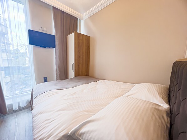 A bedroom with a bed, a wardrobe, and a window with curtains.