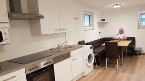 Ett modernt kök med en inbyggd ugn, en tvättmaskin och en matplats med en soffa och ett bord.