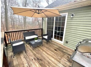 Relax and dine al fresco on this covered patio with a grill, wicker chairs, and a potted plant.